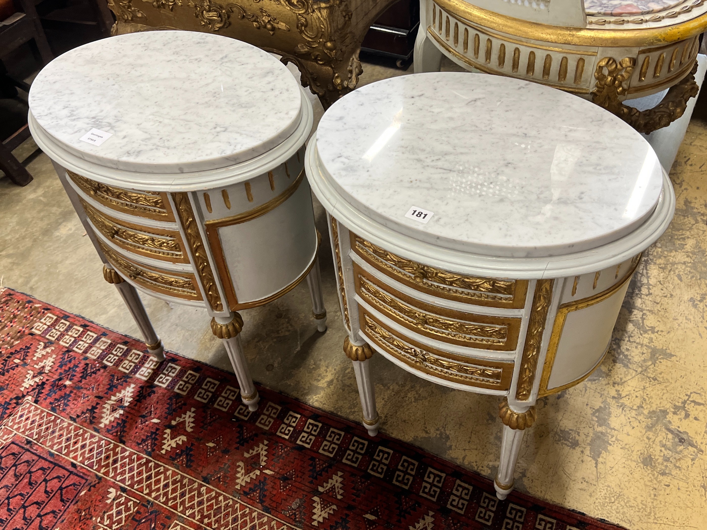 A pair of oval French marble topped bedside cabinets, width 51cm, depth 48cm, height 70cm